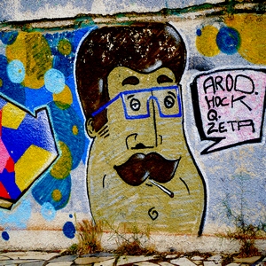Mur sur lequel est peint un portrait d'homme à la cigarette et aux lunettes bleues - France  - collection de photos clin d'oeil, catégorie streetart